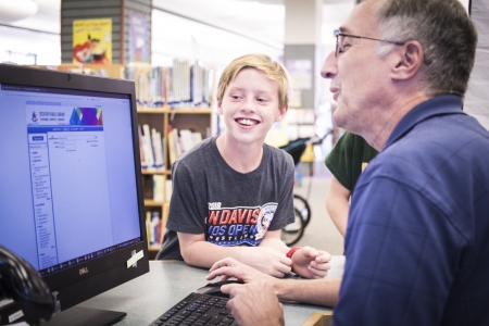 John helps a patron search for a book on the computer